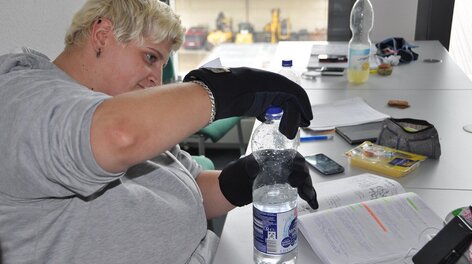 Frau öffnet Flasche mit Rheumahandschuhen