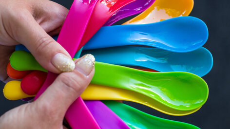 Hand mit bunten Plastiklöffeln