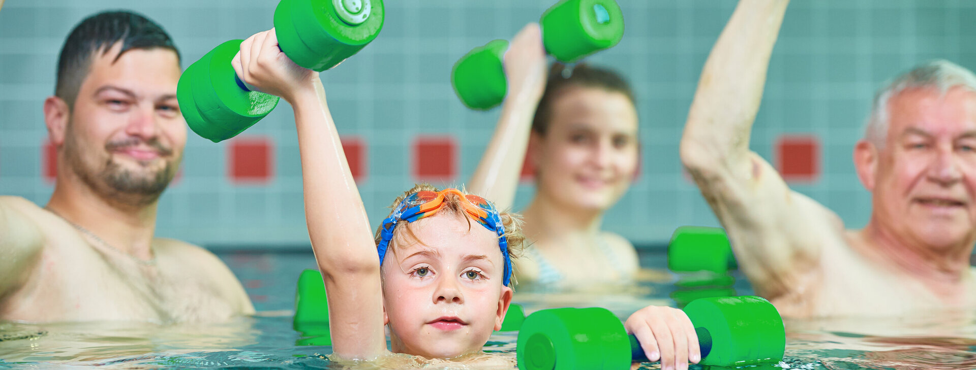 Mehrere Menschen mit Sportgeräten im Schwimmbecken