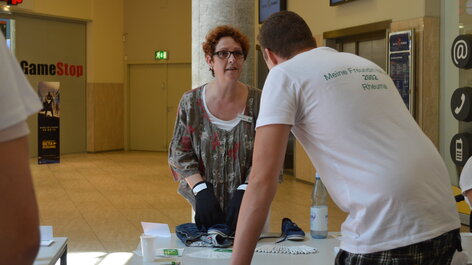 Frau mit Rheumahandschuh spricht mit Mann