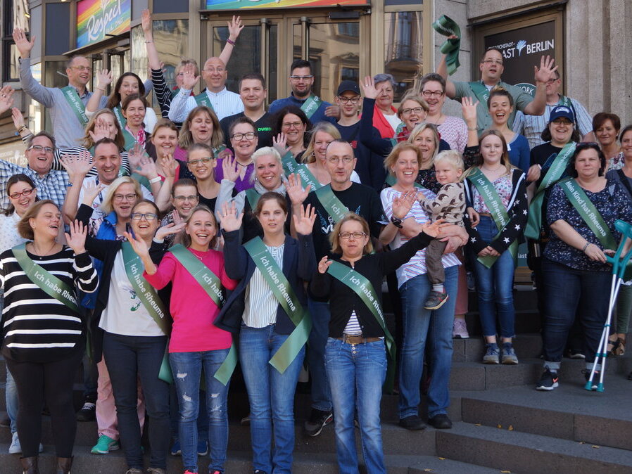 Gruppenbild mit winkenden Menschen die eine Schärpe tragen