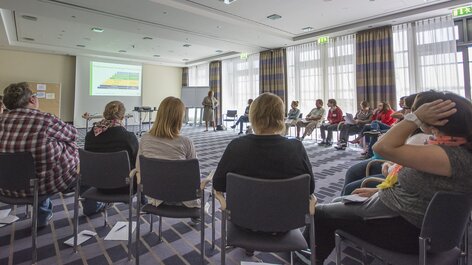 Menschen sitzen im Stuhlkreis