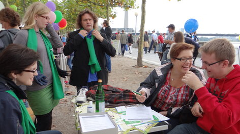 Personen mit grünen Schals sitzen an Tisch